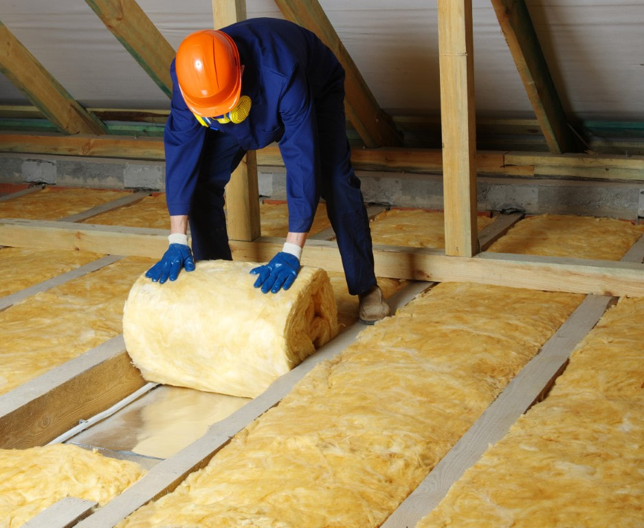 A picture of a person placing an insulation material at the attic of the house