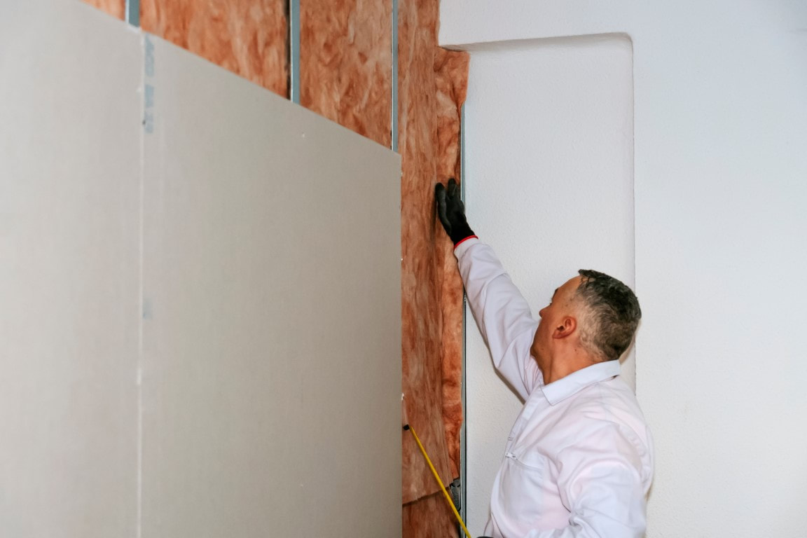 A picture of a man measuring the area for insulation material placement