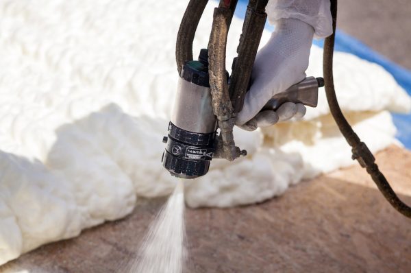 close up view of a spray foam insulation application nozzle spraying foam