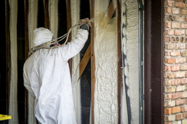 worker applying spray foam insulation to interior garage walls - menlo park